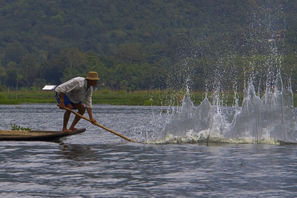 Fisherman whack the water to attract the fish on Lake Inle in Myanmar